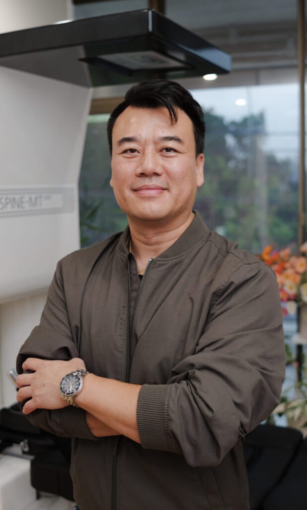 Chiropractor Brandon Ngo in his clinic at Taringa Chiropractic with a spinal decompression machine in the background.