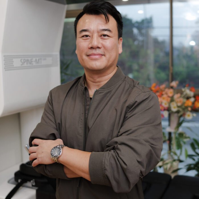 Chiropractor Brandon Ngo in his clinic at Taringa Chiropractic with a spinal decompression machine in the background.